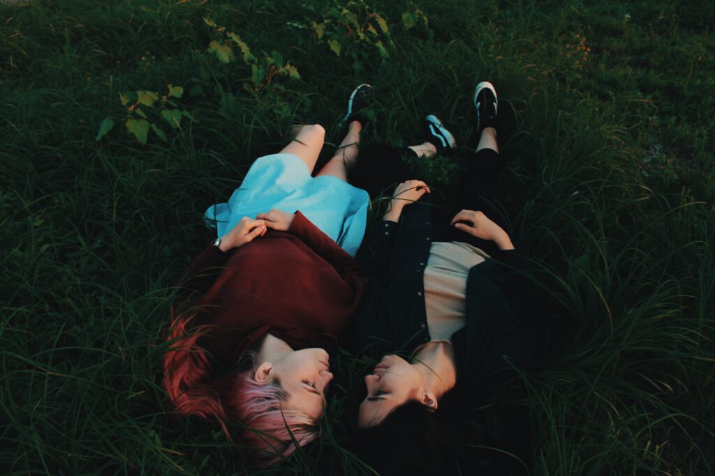 Two women smiling on grass looking at each other