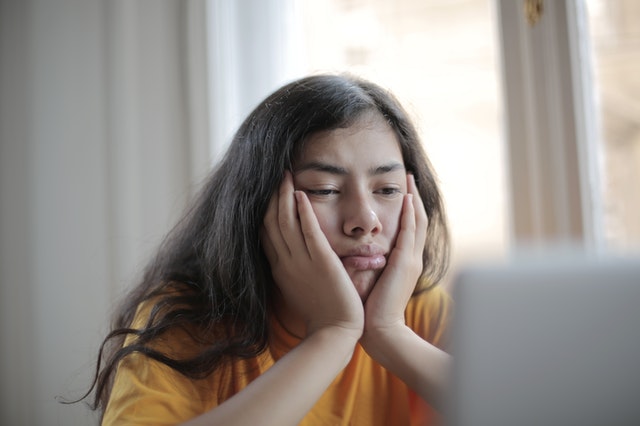 Woman sitting with her head in her hands, looking sad and annoyed