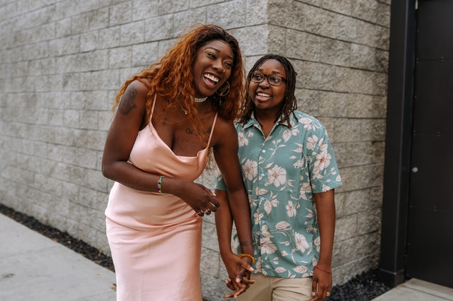 A female couple laughing and holding hands while walking 