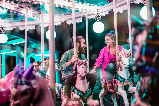 couple holding hands on horse carousel
