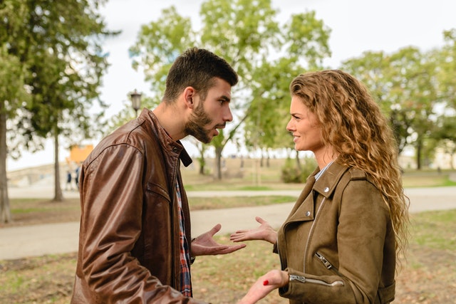 A man and woman facing each other looking annoyed