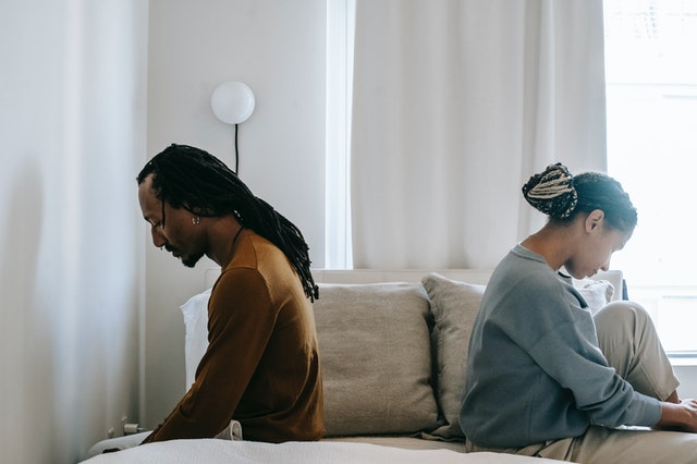 Man and woman sitting with their backs to each other looking troubled