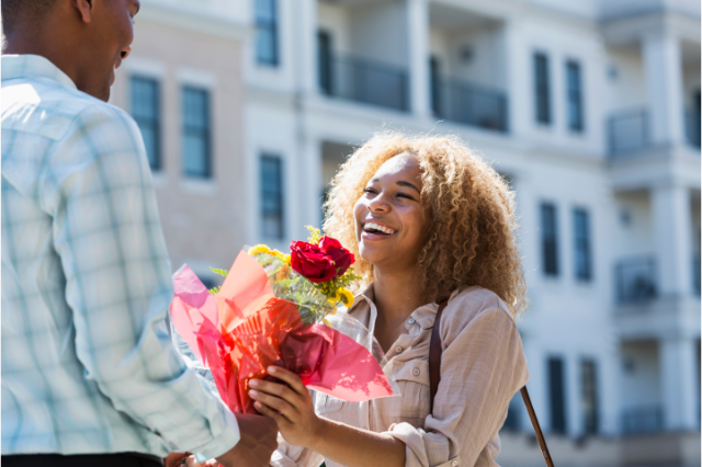 Man handing over flowers to a smiling woman