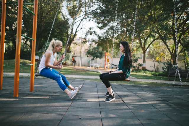 Women chatting while sitting on swings