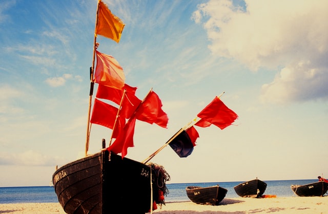 Beached boat with a lot of red flags in it