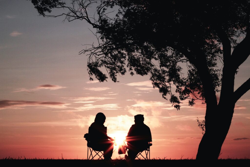 Two people sitting in front of a sunset