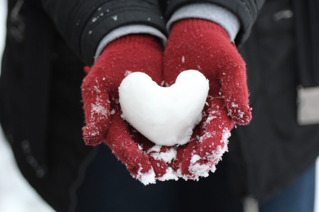 A heart-shaped snowball held in red gloves