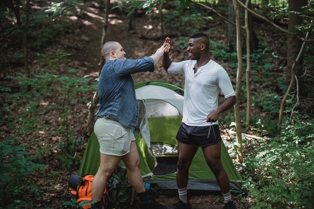 Couple camping and high-fiving outside a tent