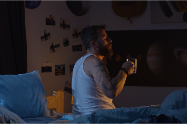 Man sitting on a bed with a cup of tea