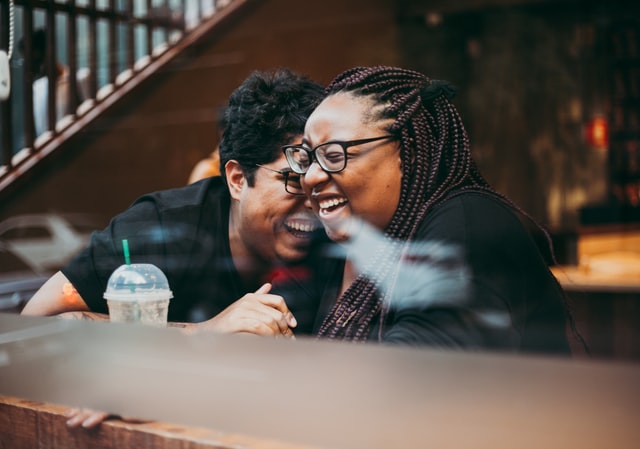 Couple laughing together, hugging in a coffee shop.