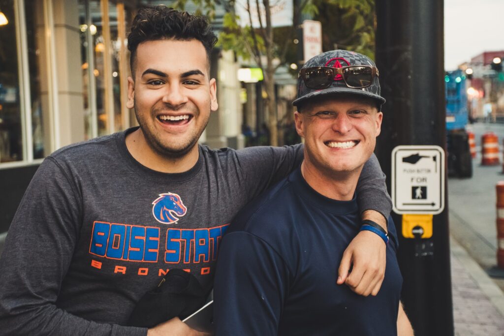 Two men, arm in arm, cheesing at the camera