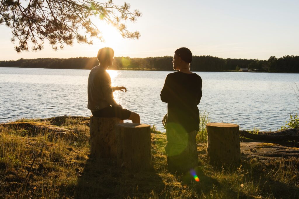 Two people sitting my a lake talking