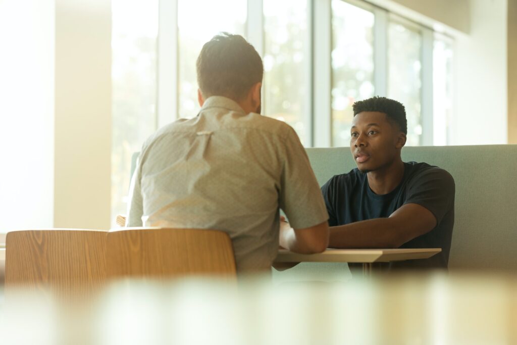 two men sitting at a table having a conversation