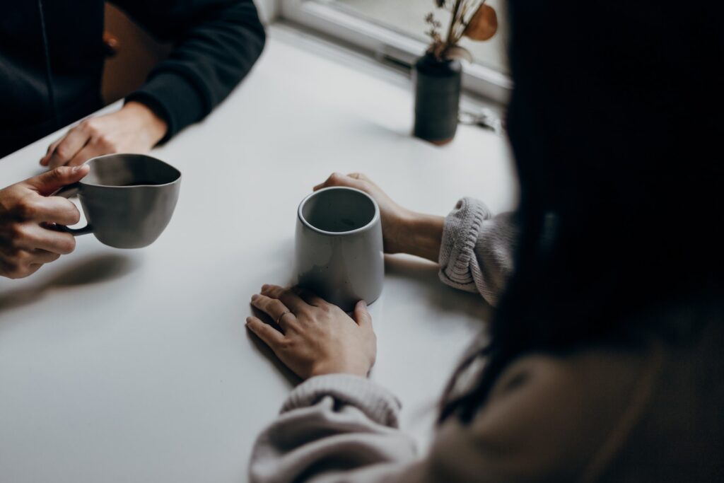 Two people in long sleeves, holding ceramic mugs