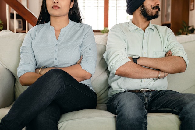 man and woman sitting on couch ignoring each other